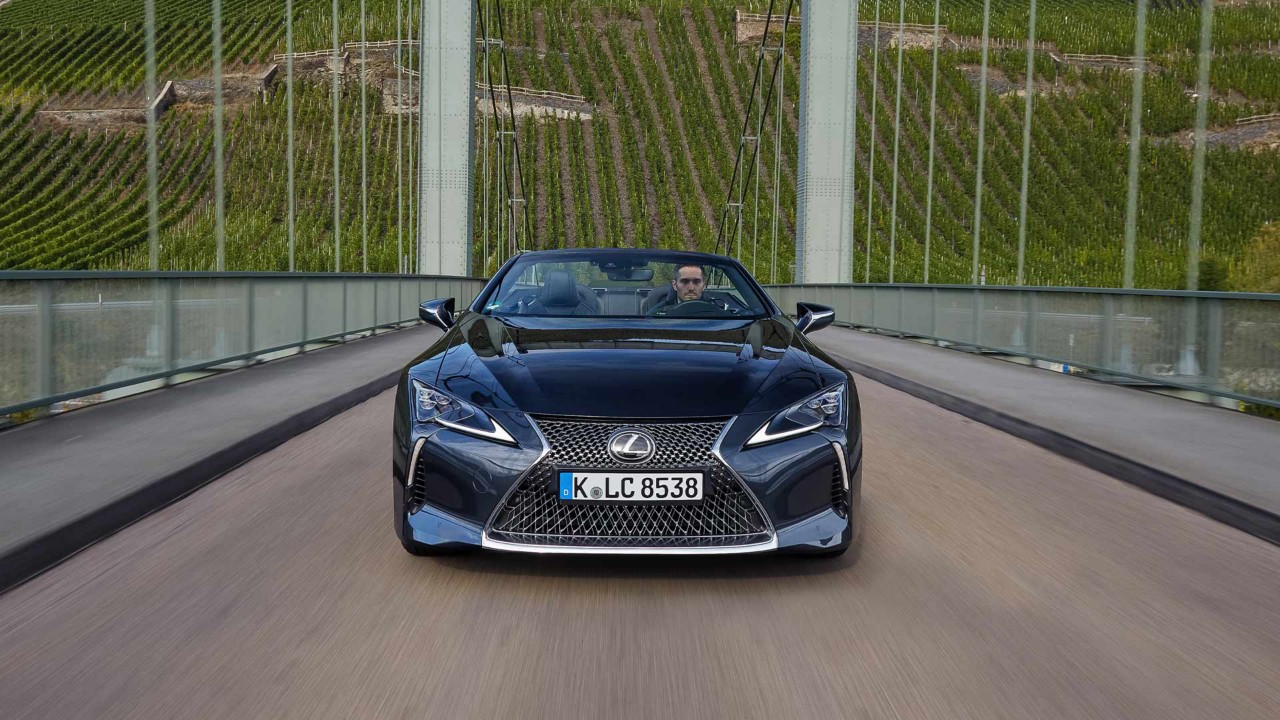 Der neue Lexus LC500 fährt gemütlich über eine Brücke durch die Weinberge.