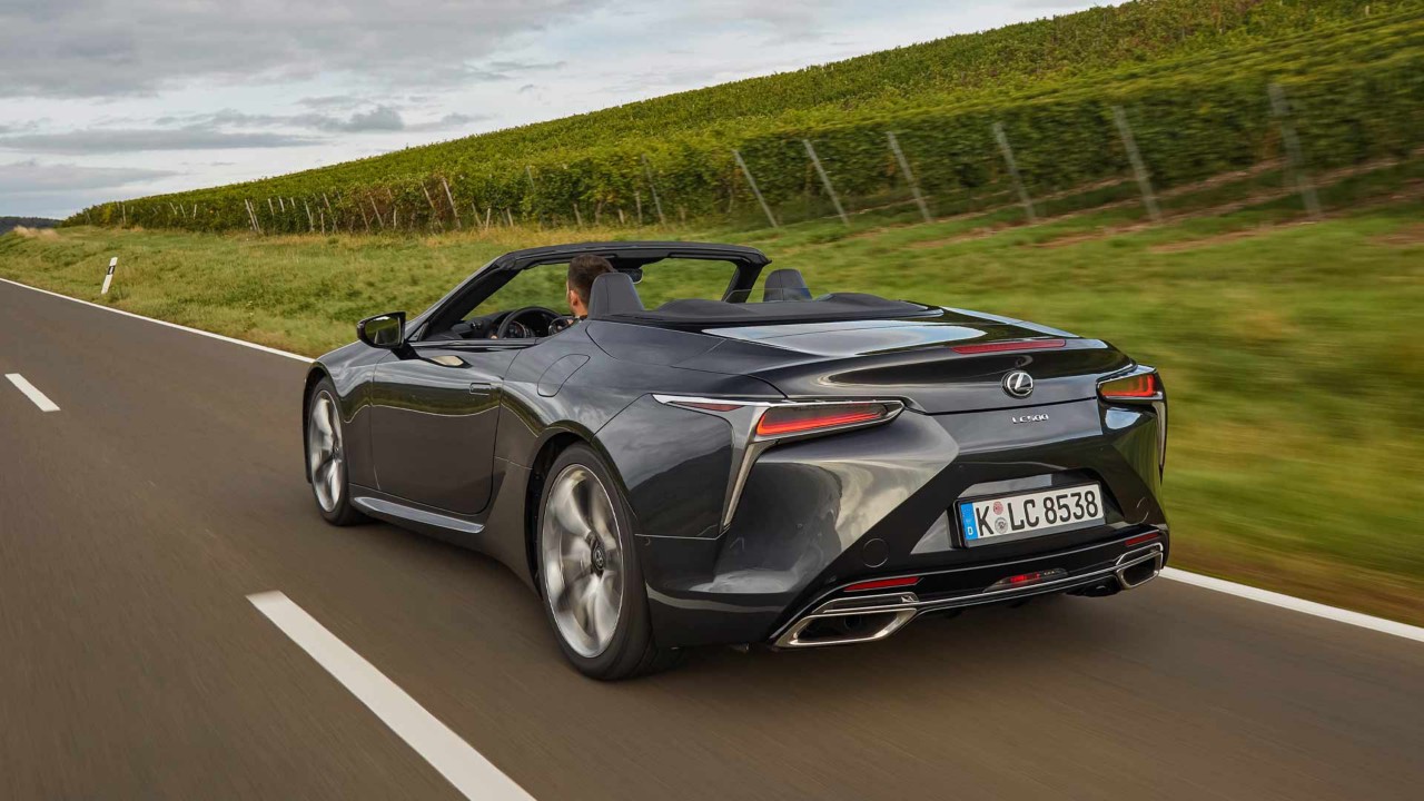 Hinteransicht des neuen  Lexus LC500 der gemütlich auf einer Straße durch Weinberge fährt.