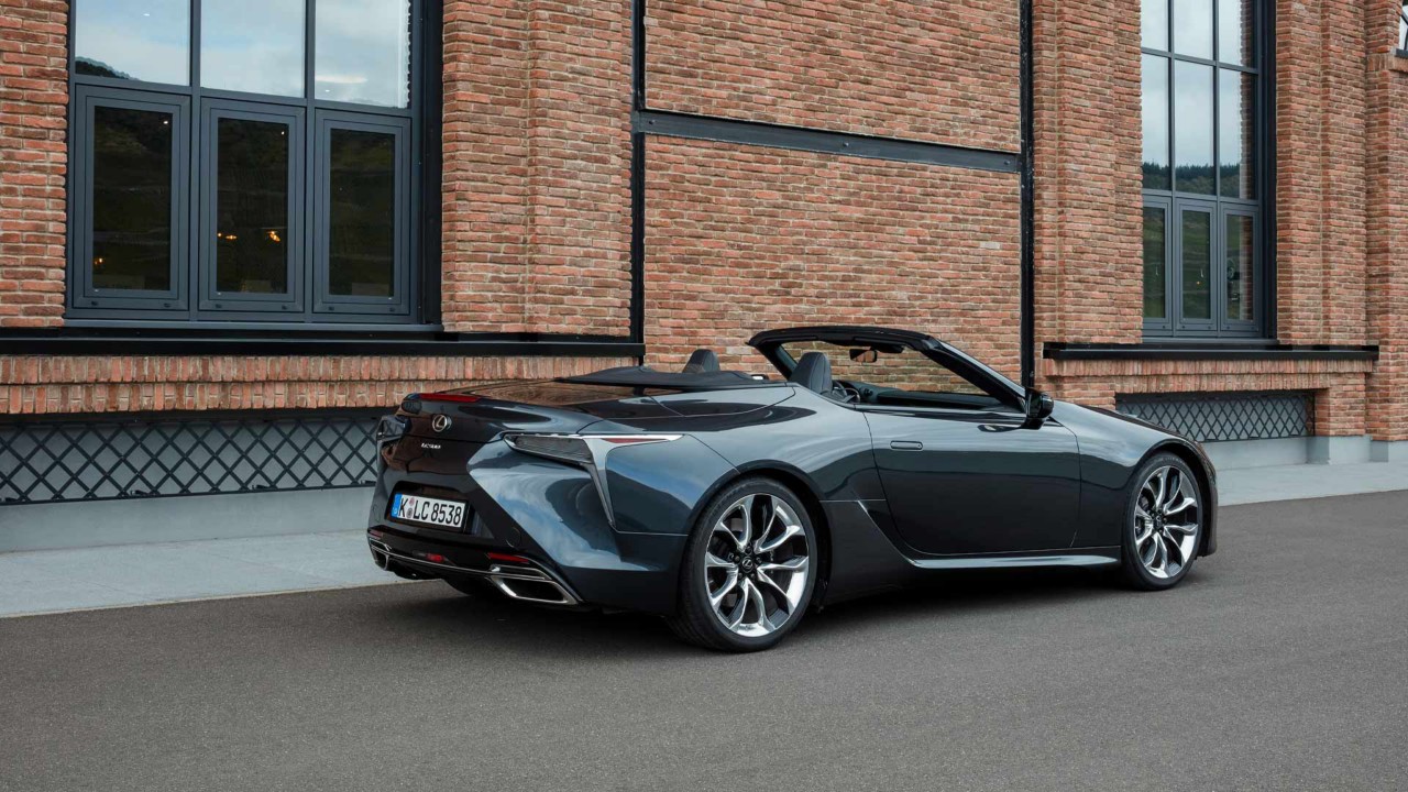 Hintere Seitenansicht des LC Cabriolet vor einem Backsteinhaus.