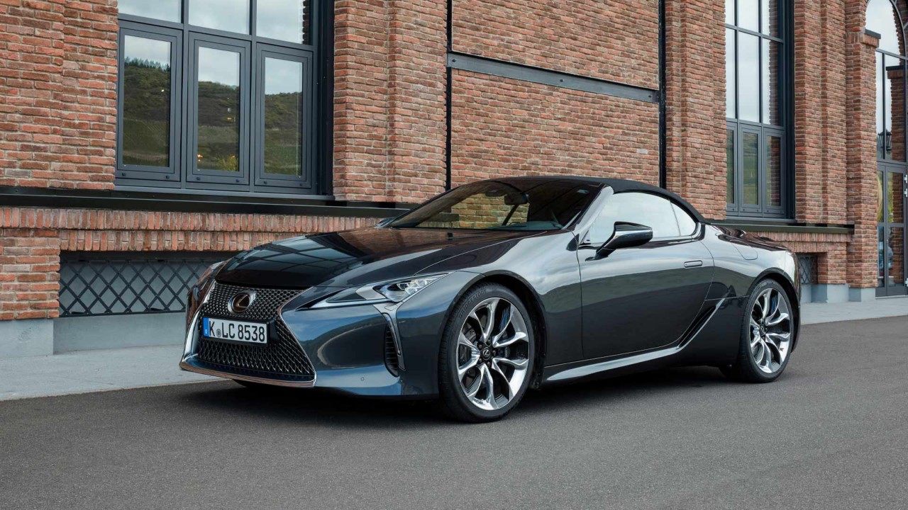 Lexus LC Cabriolet mit geschlossenem Dach vor einem Backsteinhaus.