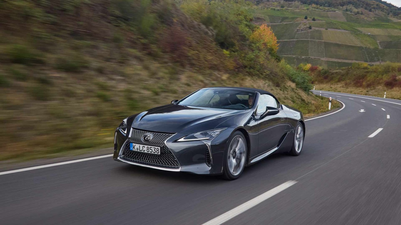 Lexus LC Cabriolet mit geschlossenem Dach vor einem Backsteinhaus.