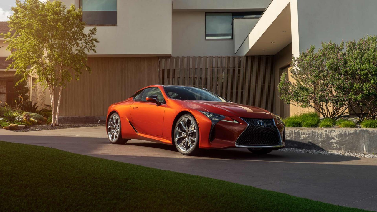 Lexus LC Coupé vor einem modernen Wohnhaus an einem Sommerabend.