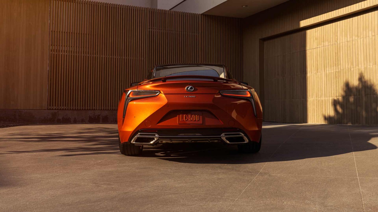Hinteransicht eines Lexus LC Coupé vor einem Haus an einem Sommerabend.