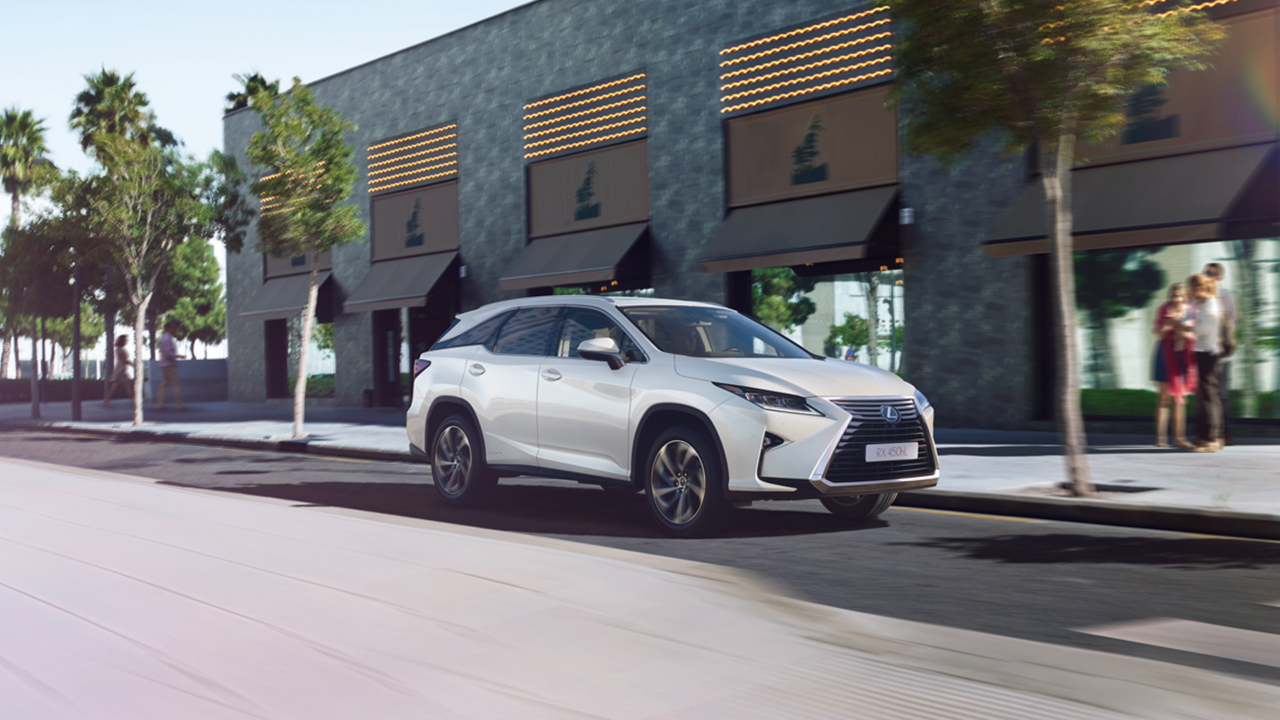 Ein silberner Lexus RX L fahrend auf einer Straße in moderner Umgebung